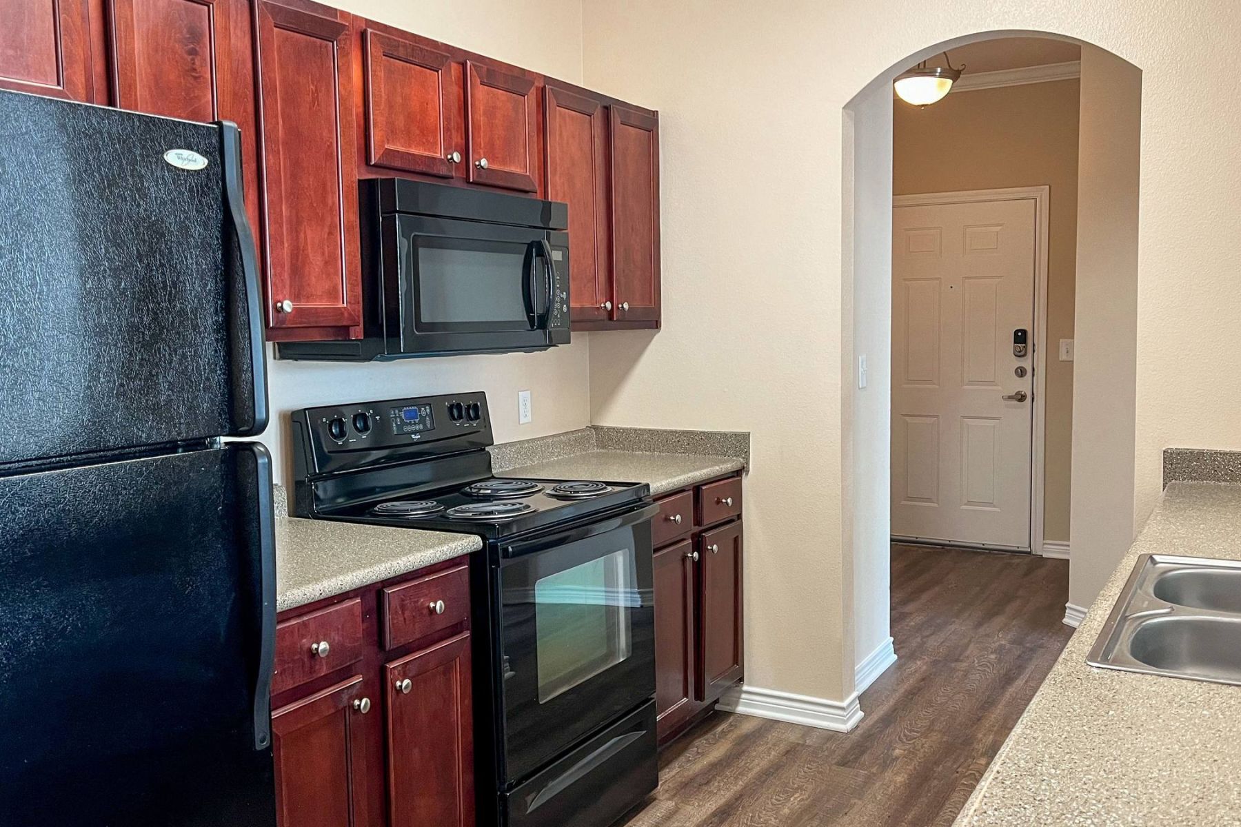 Empty room with wood floors, ceiling fan, and sliding glass door leading to a patio with vertical blinds at Apex West Midown.
